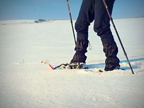 Man legs with snowshoes walk in snow. Detail of winter hike in snowdrift
