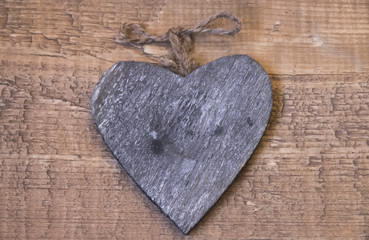Wooden vintage gray heart with a cord of twine for the interior on a wooden surface