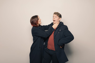 Happy young couple in winter clothes having fun in studio over white background