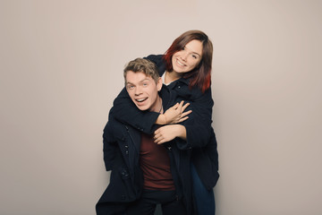 Happy young couple in winter clothes having fun in studio over white background