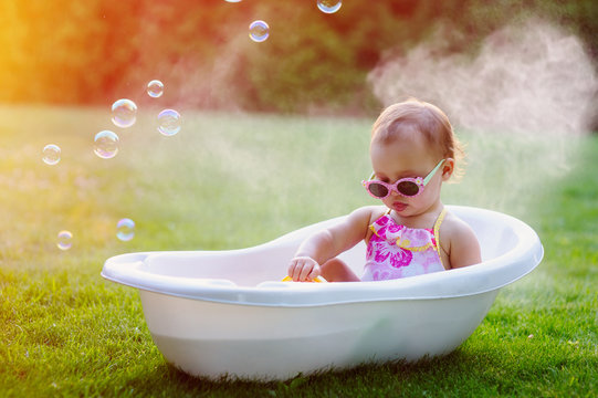 little baby girl bathes in bath on meadow