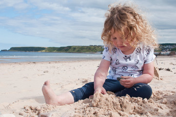 Fototapeta na wymiar Little girl on a sandy beach playing