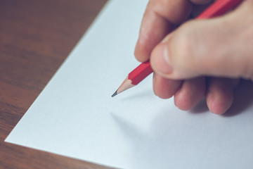 A close photo of a persons writing a letter with a pencil