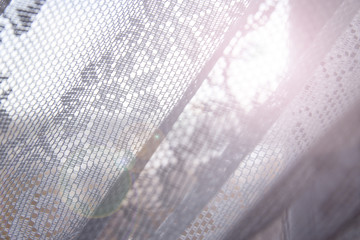 Sun shines through tulle with openwork pattern