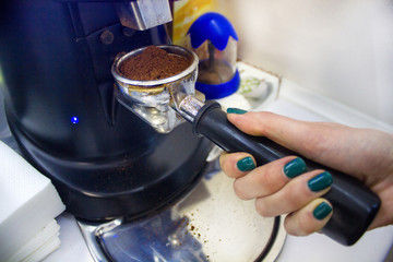 woman's hand taking ground coffee from coffee-grinder