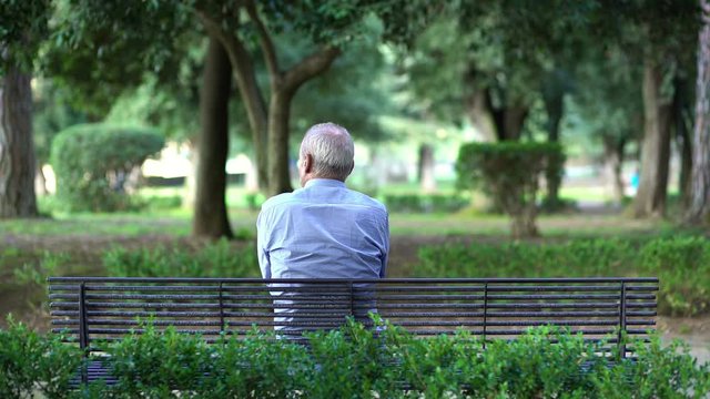 Grandpa alone, sitting on a bench waiting for the grandchildren