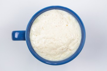 close up top view spoiled milk in blue glass on white background, bad milk, concept healthy 