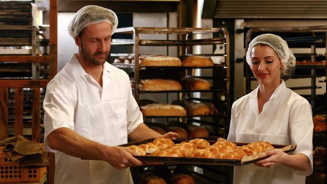 Portrait of bakers removing baked michetta from baking trolley in bakery kitchen 4k