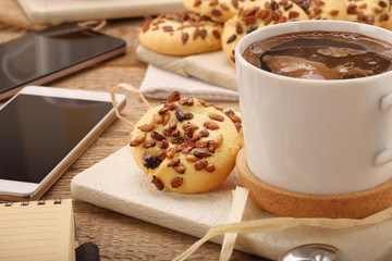 Cup of coffee cup with crunchy cookie on the table and smart pho