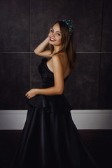 Young beautiful woman in long black dress and diamond crown