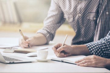 Two guys writing in notepad closeup