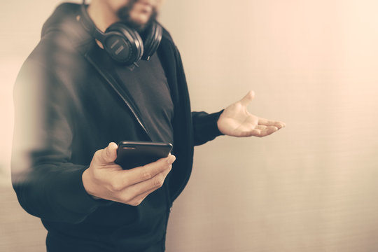 hooded man hipster with headphones listening to music with smart