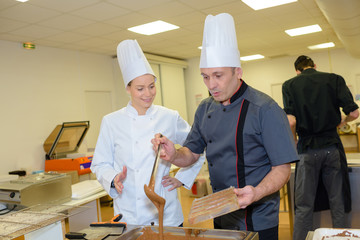 team of pastry chefs preparing chocolate sweets in the kitchen