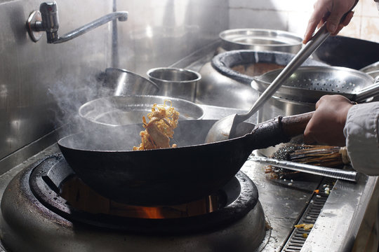 Chef preparing chinese food in vok pan at restaurant