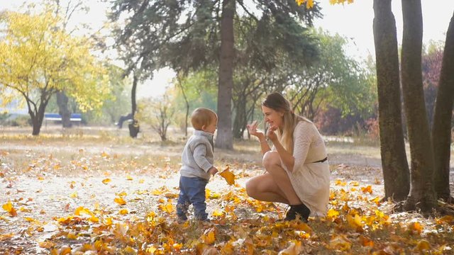 Slow motion footage of cute baby boy making first to his mother at autumn park