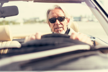 Senior Man Driving A Convertible Classic Car