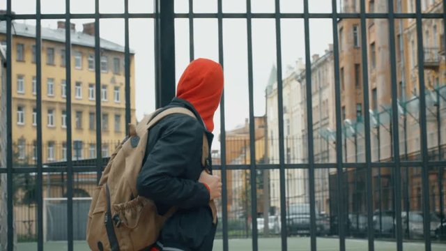 Young student teenager boy's legs in grey sports trousers and sport sneakers shoes walk to the play ground in the backyard of apartment house in old city district