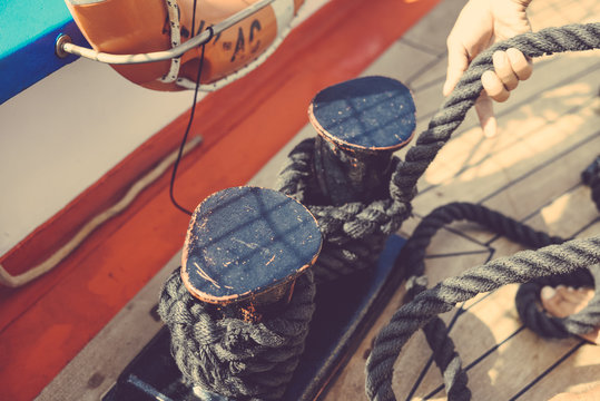 Closeup on hands holding tackle marine rigging and ropes wooden deck background