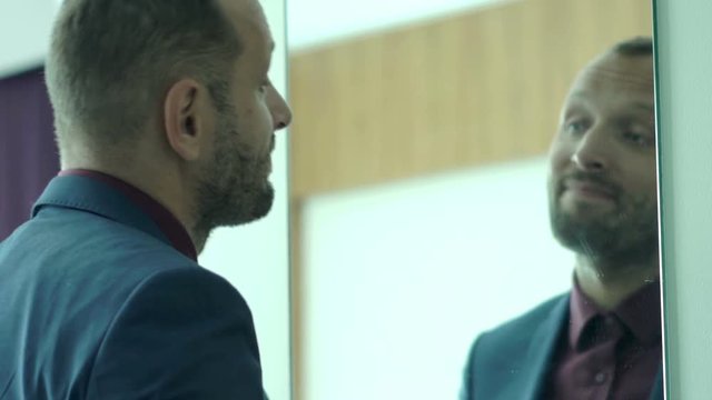 Young businessman checking his appearance in mirror and motivate himself

