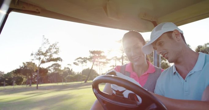 Golfers sitting in golf buggy using mobile phone at golf course