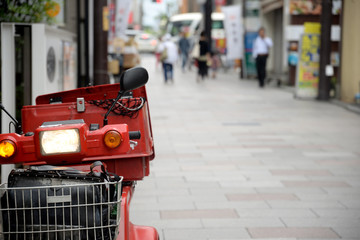 Czerwony skuter trójkołowiec stojący na ulicy - obrazy, fototapety, plakaty