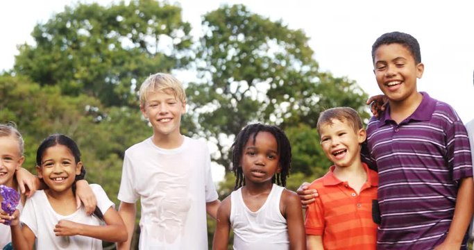 Group of smiling kids standing together with arms around in garden on a sunny day 4k