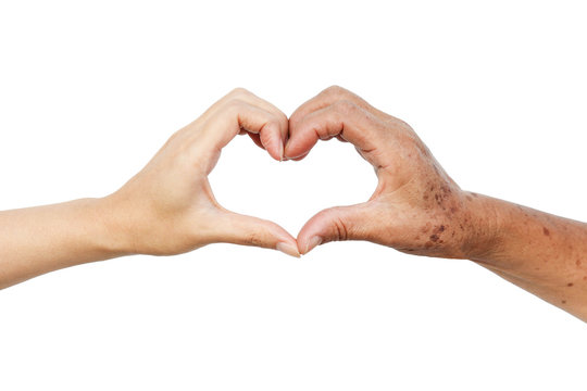 Hands of the female elderly and a young woman forming a heart shape together / Love and care elderly people concept