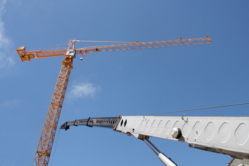 Tower and telescope cranes against blue sky