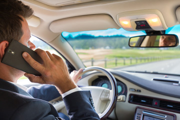 Businessman talking on cell phone while driving and overtaking, not paying attention to the road...