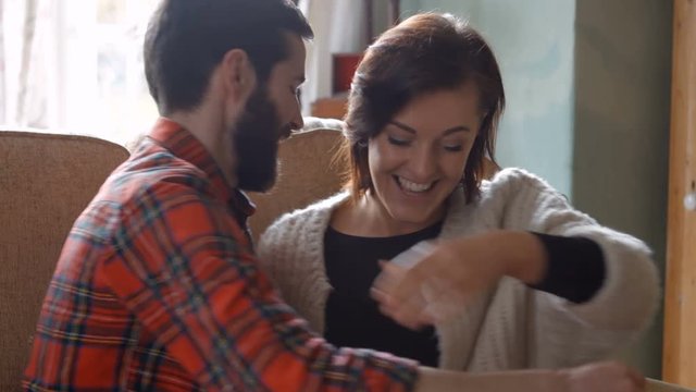 Woman receiving a gift by man in the living room at home 