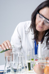 Female Laboratory Staff Working With Flasks Filled with Liquids. Vertical Image