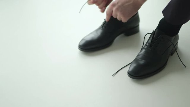 Man tying patent leather shoes.