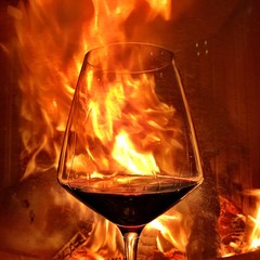 Red wine glass in front of a fireplace