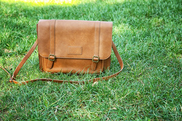Brown leather handbag on green grass
