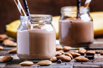 Banana-chocolate smoothie with almonds in glass jars, vintage wo