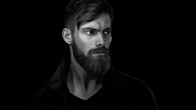Black and white portrait of bearded handsome man in a pensive mo