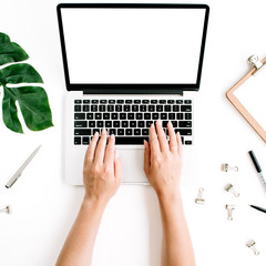 Workspace with hands typing on laptop with blank screen. Flat lay, top view