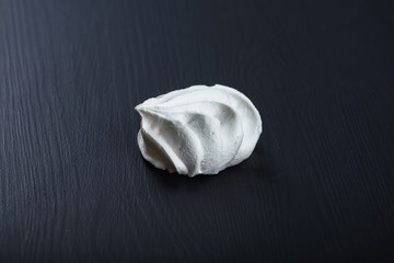 Single fluffy meringue on black table