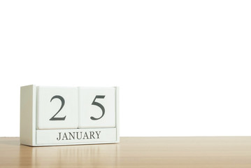Closeup surface white wooden calendar with black 25 january word on blurred brown wood desk isolated on white background with copy space , selective focus at the calendar