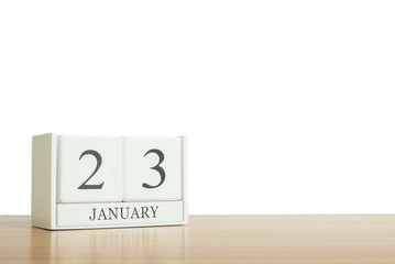 Closeup surface white wooden calendar with black 23 january word on blurred brown wood desk isolated on white background with copy space , selective focus at the calendar