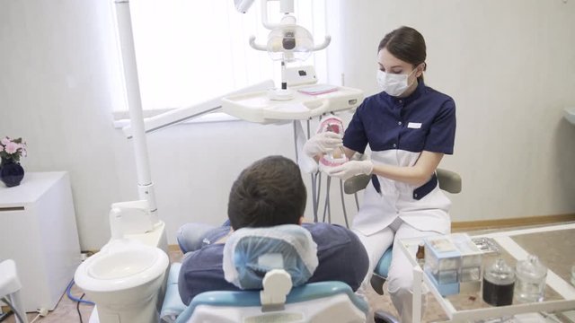 Dentist young woman making procedures to men patient at dental office. Concept of healthy life
