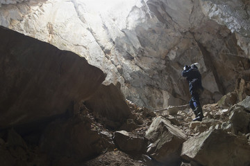 Caver in a helmet and with a lantern in the cave makes the output picture in the rays of light