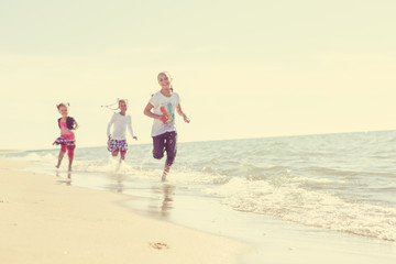 Fototapeta na wymiar Kids running at the beach, focus on sand in foreground