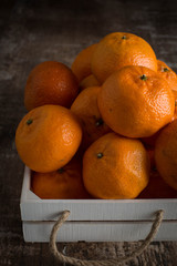 A white wooden crate full of tangerines