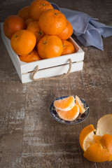 A peeled tangerine and a crate full of tangerines. Rustic weathered wood background. 