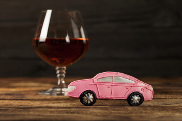 Small baby car with glass of brandy on wooden table