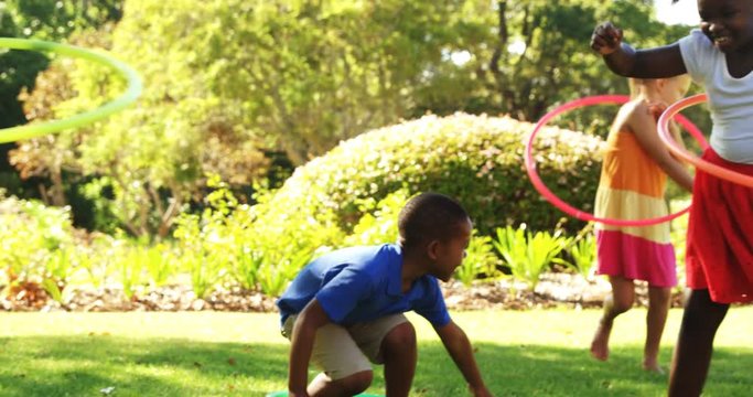 Group of kids twirling hula hoop in park on a sunny day 4k