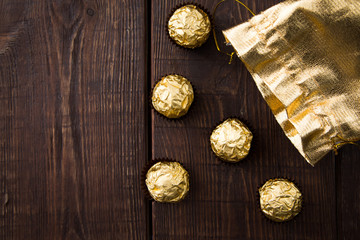 Fototapeta na wymiar gold bag of chocolates. candy in Golden foil with copy space