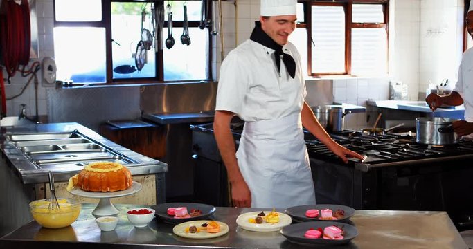 Smiling chef leaning on dessert counter in restaurant kitchen 4K