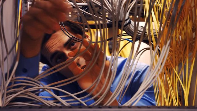 Attentive technician fixing cable in server room 4k